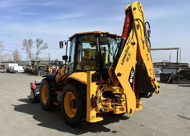 Yellow backhoe with raised arm, parked outdoors on a sunny day.