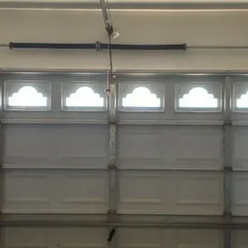 Empty white garage with closed double doors and speckled gray floor