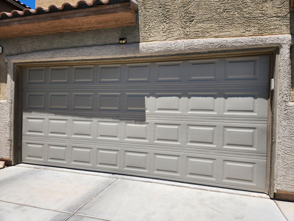 Modern house exterior with gray garage door and front entry, plus a potted shrub by the door