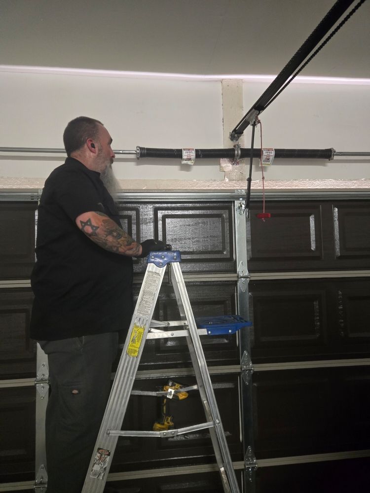 Two workers in orange hard hats lifting a garage door in a warehouse loading bay