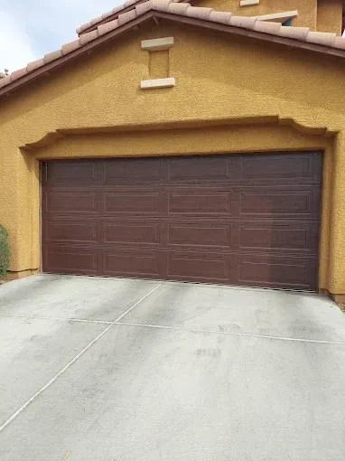 Two-car garage with gray doors and stone exterior in a suburban home driveway