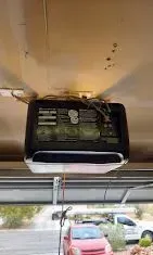 Open garage door with overhead opener and tracks in a bright empty garage