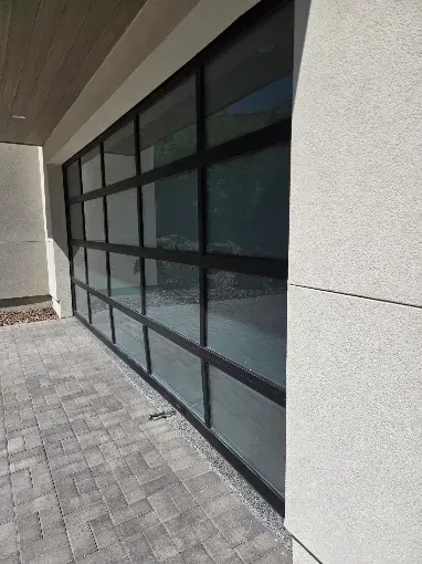 Garage door under construction with white insulated panels and metal tracks in an unfinished room