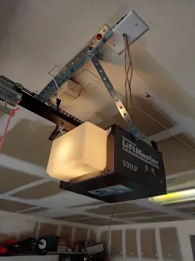 Garage door opener mounted to a ceiling track on a white ceiling