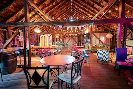 Colorful rustic attic lounge with wooden beams, round tables, and string lights