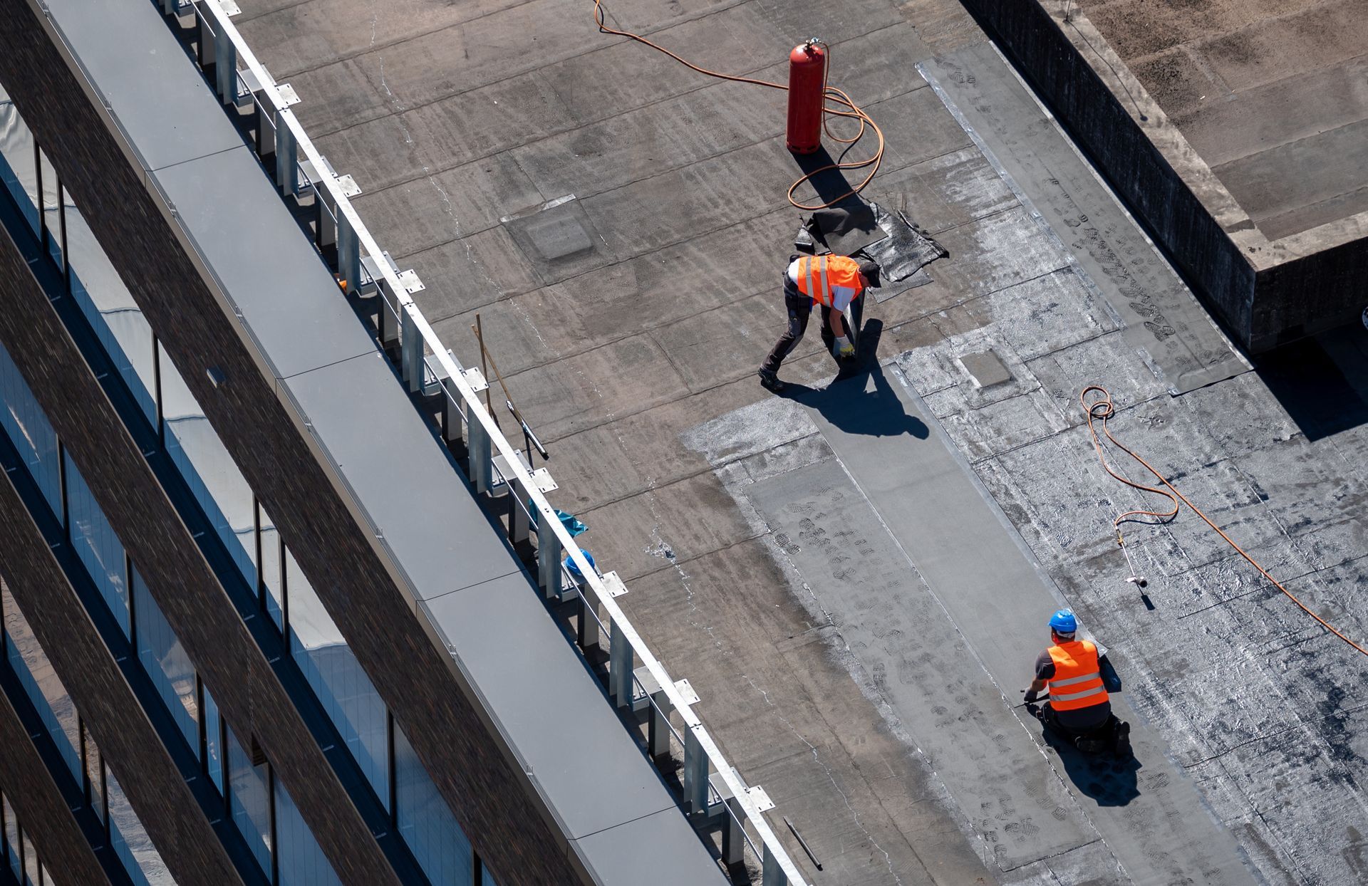 Workers installing a roof waterproofing membrane.