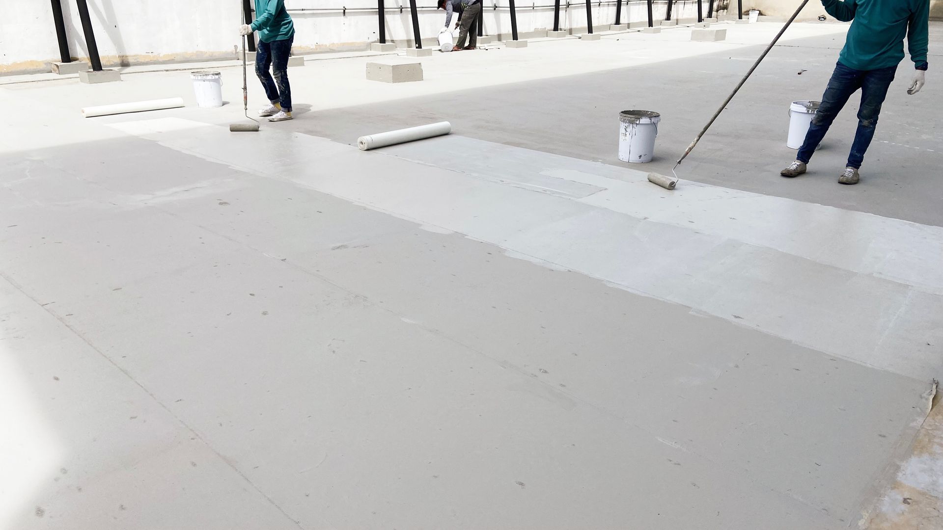 Workers applying liquid waterproofing on the rooftop surface.