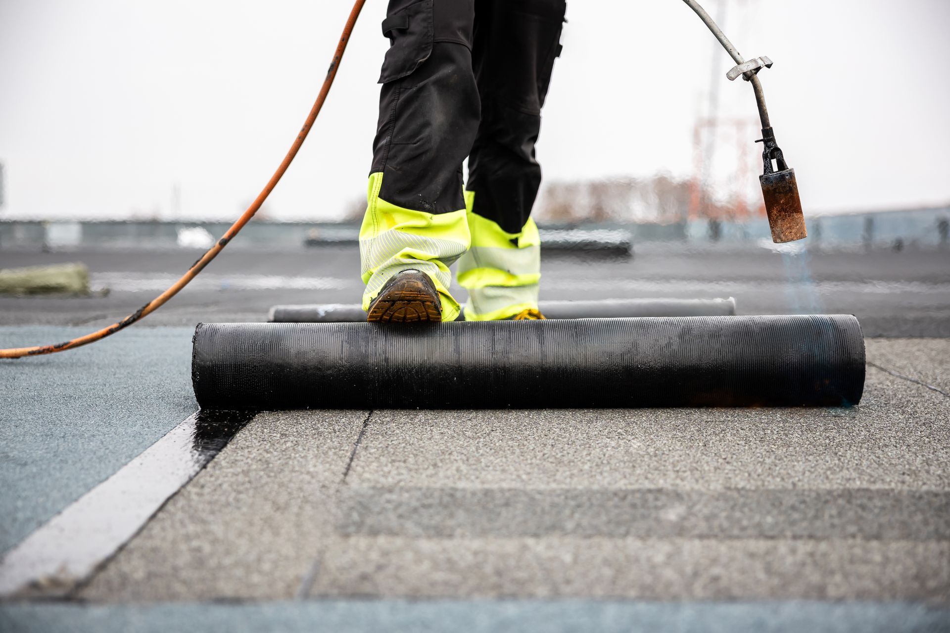 Roof waterproofing work being applied to a flat roof surface by a technician.