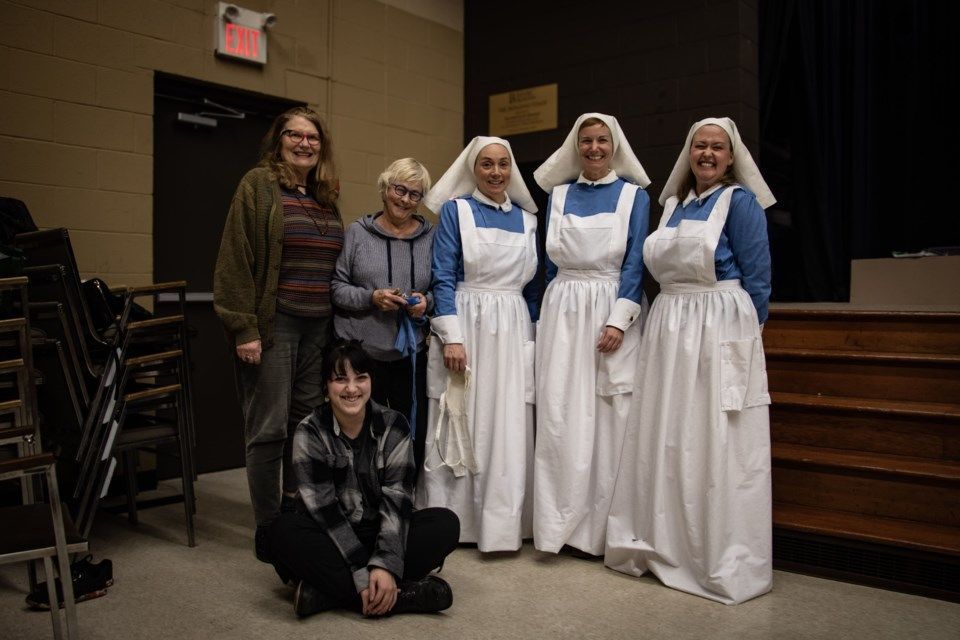 Group poses: people with women in historical nursing uniforms.