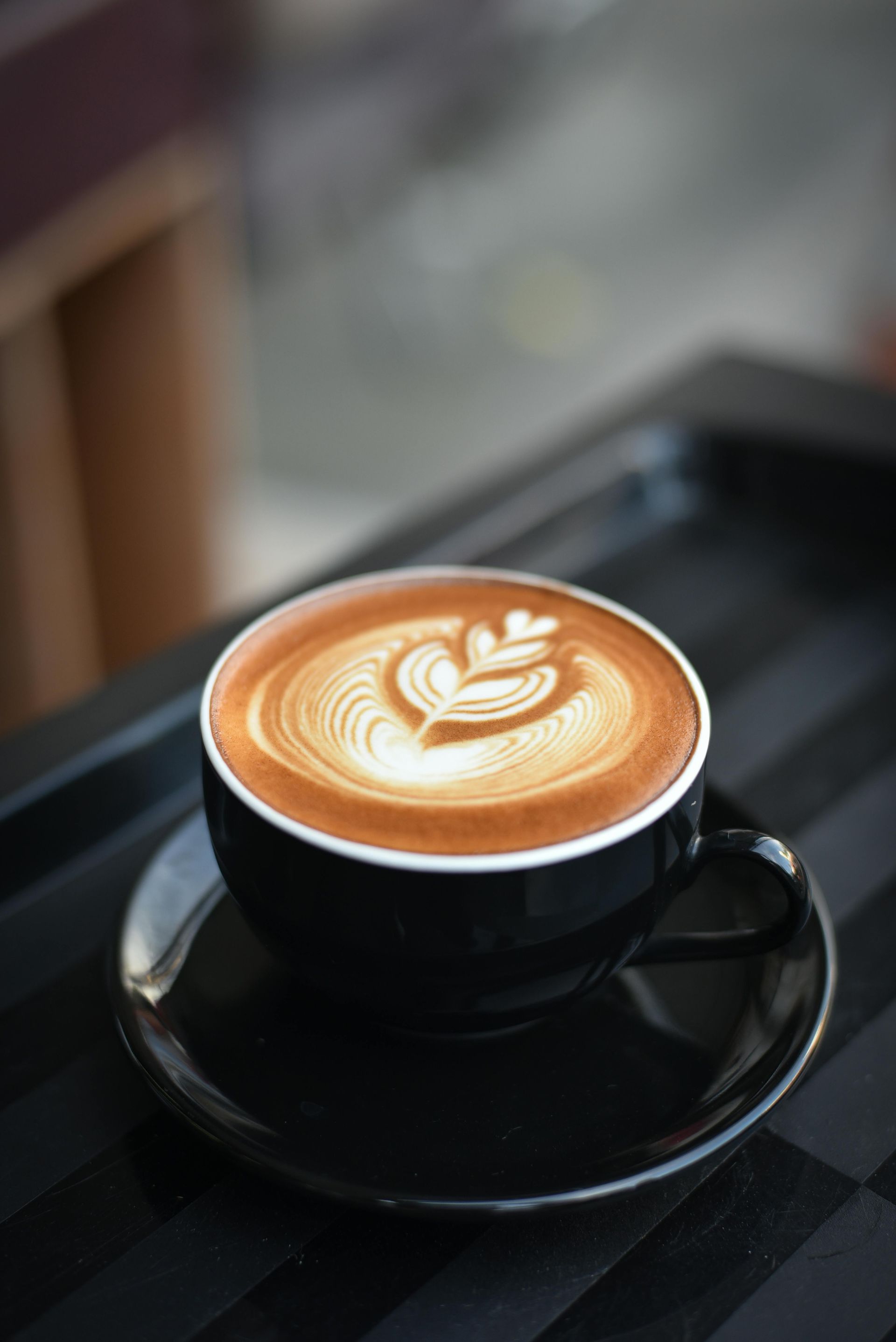 A close up of a cup of cappuccino on a saucer on a table.