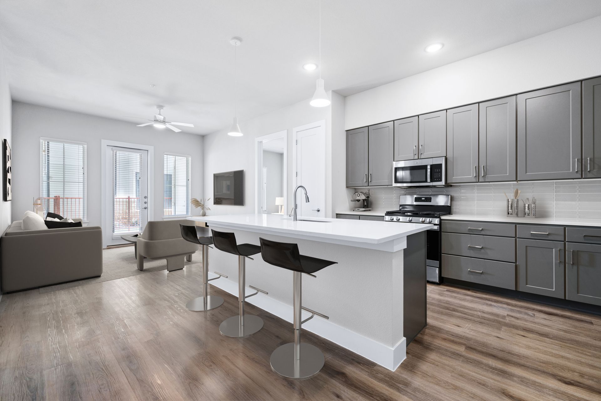 A kitchen with a large island and stools in a living room at The Wyatt, offers luxury apartments with gas stove in North Austin, TX.