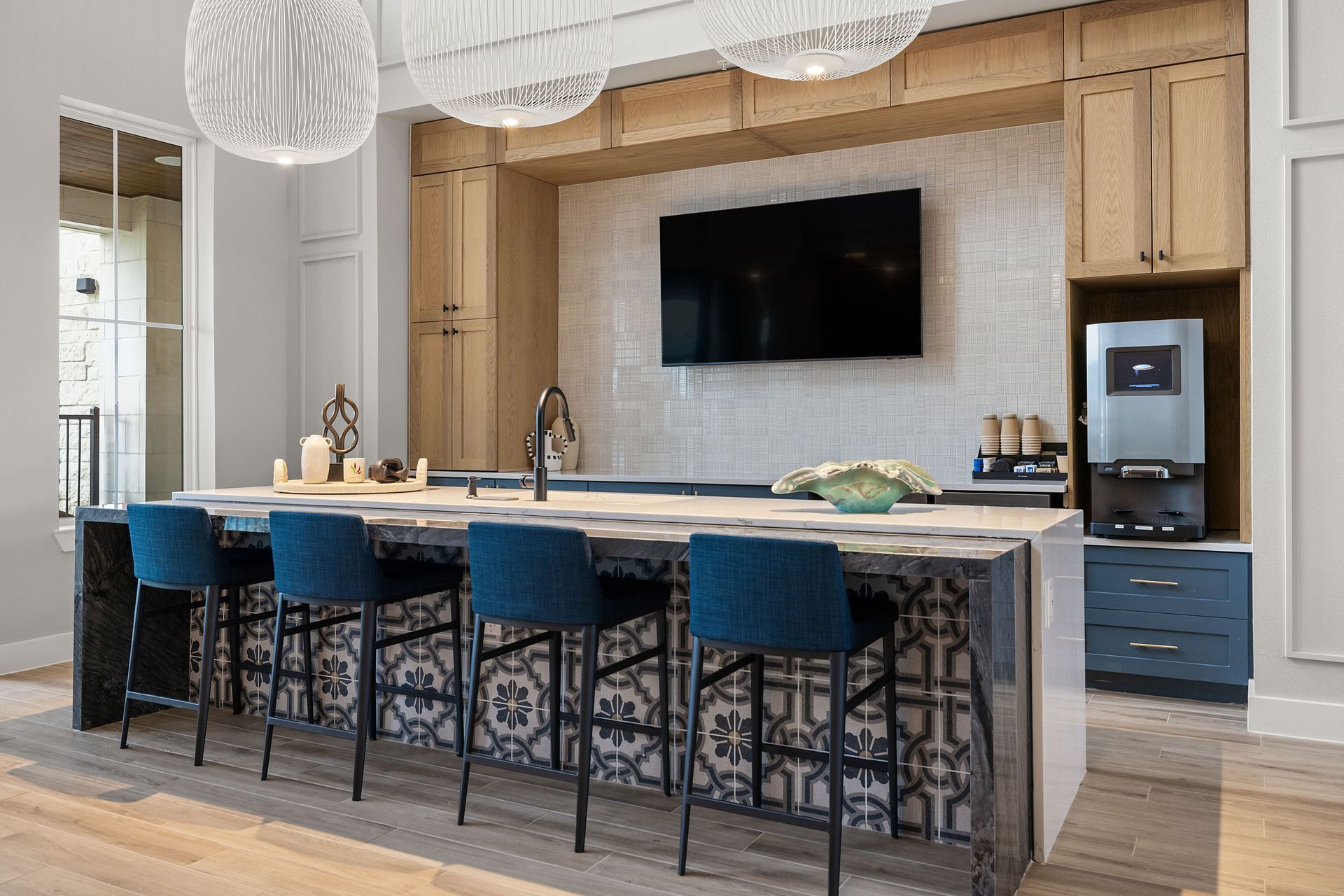 Kitchen island with blue stools and a patterned backsplash, cabinets, and a coffee machine at The Wyatt, offer luxury apartments Cedar Park.