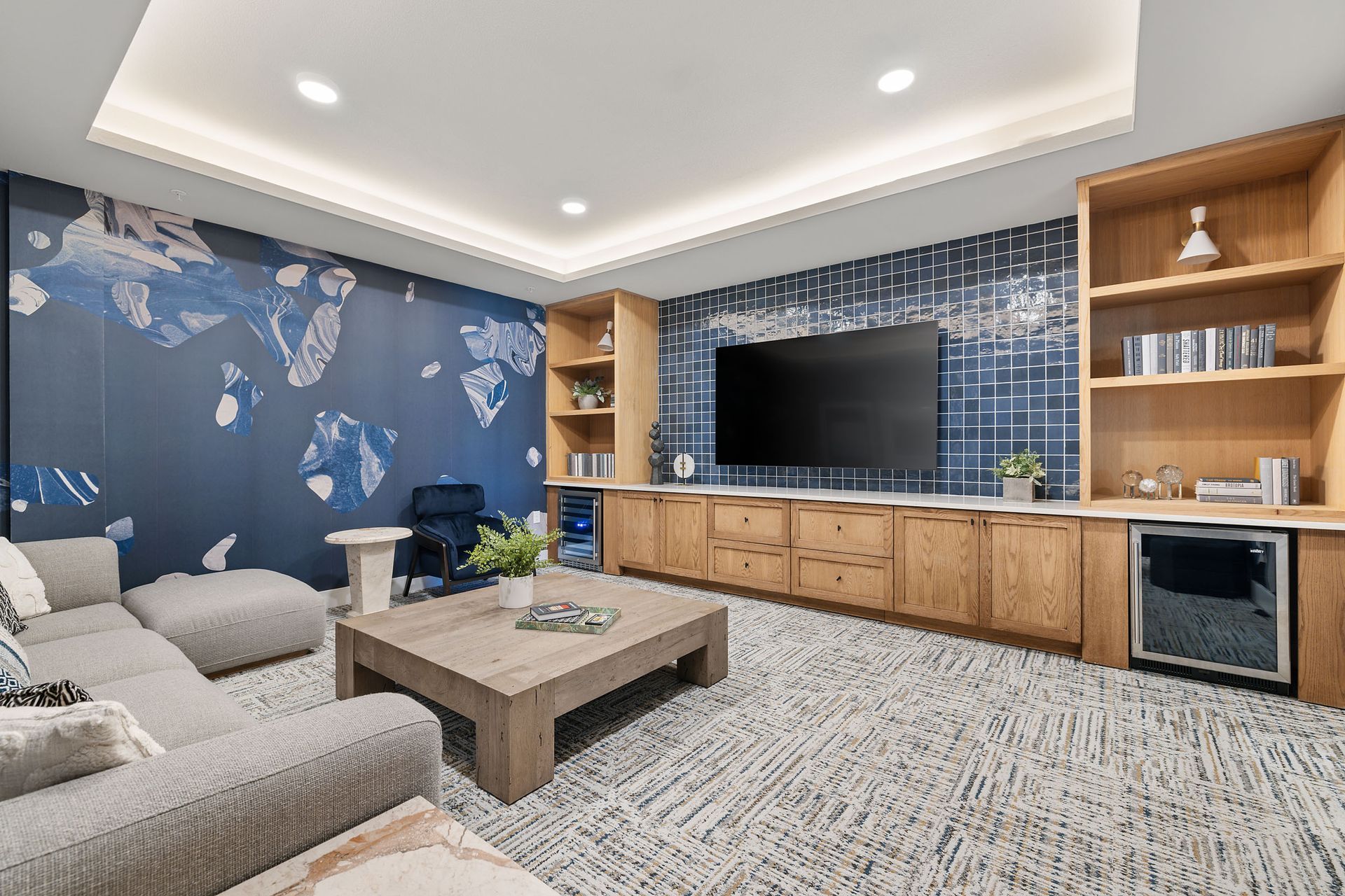 Modern media room with a large TV, built-in shelving, and a sectional sofa at The Wyatt, offering luxury apartments Cedar Park.