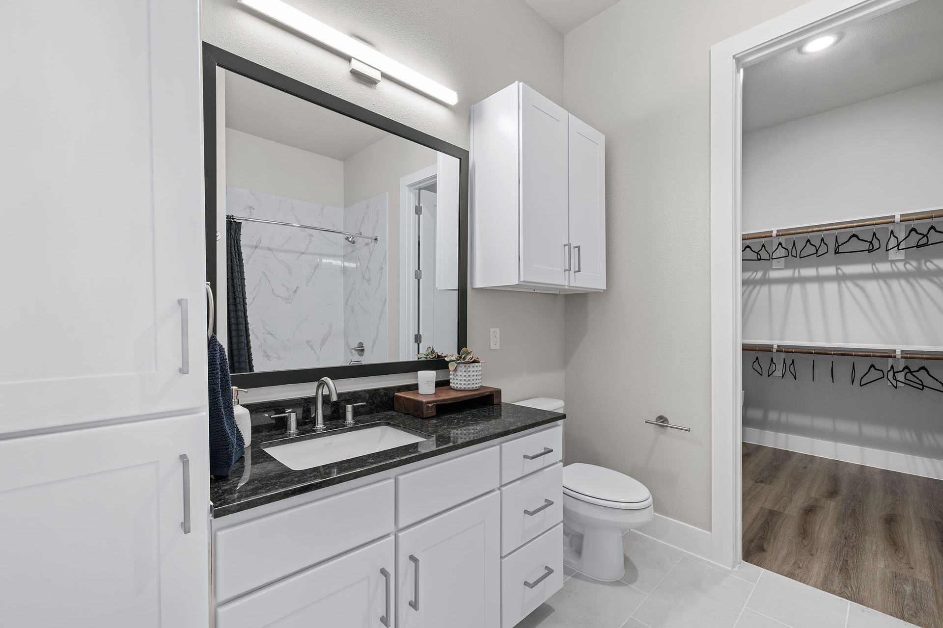 A bathroom with a sink, toilet, mirror,
and closet at The Wyatt, offers luxury apartments in North Austin, TX.