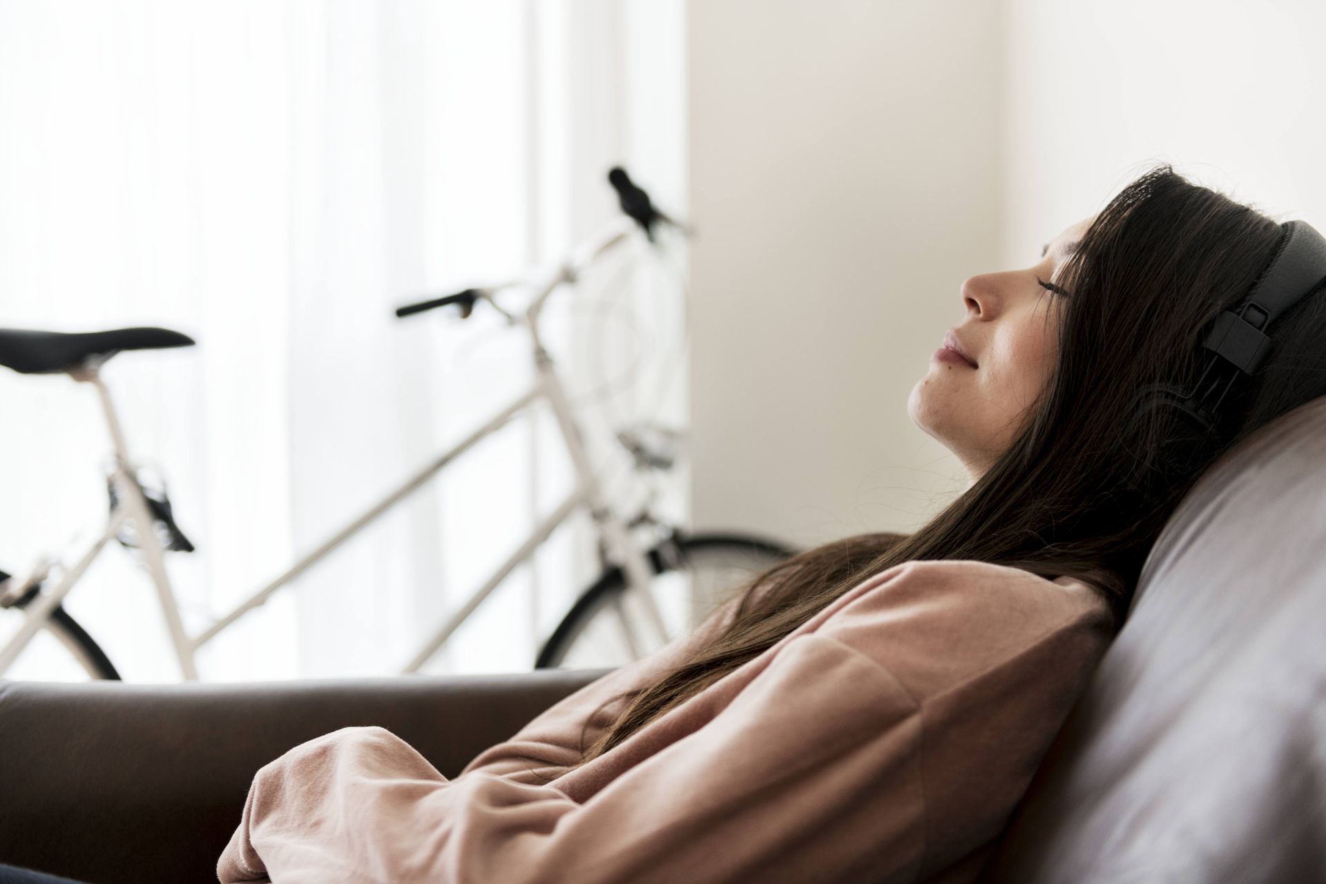 A woman laying on the sofa with a bike right next to her.