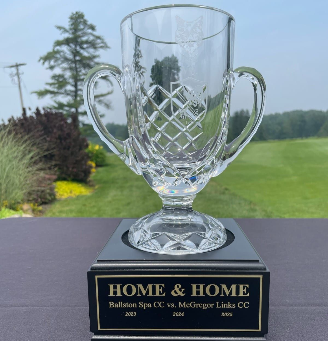 A crystal trophy cup with a black plaque reading