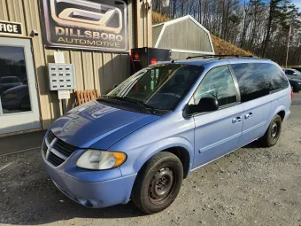 Light blue minivan parked outside a Dillsboro Automotive shop on a gravel lot | Dillsboro Automotive