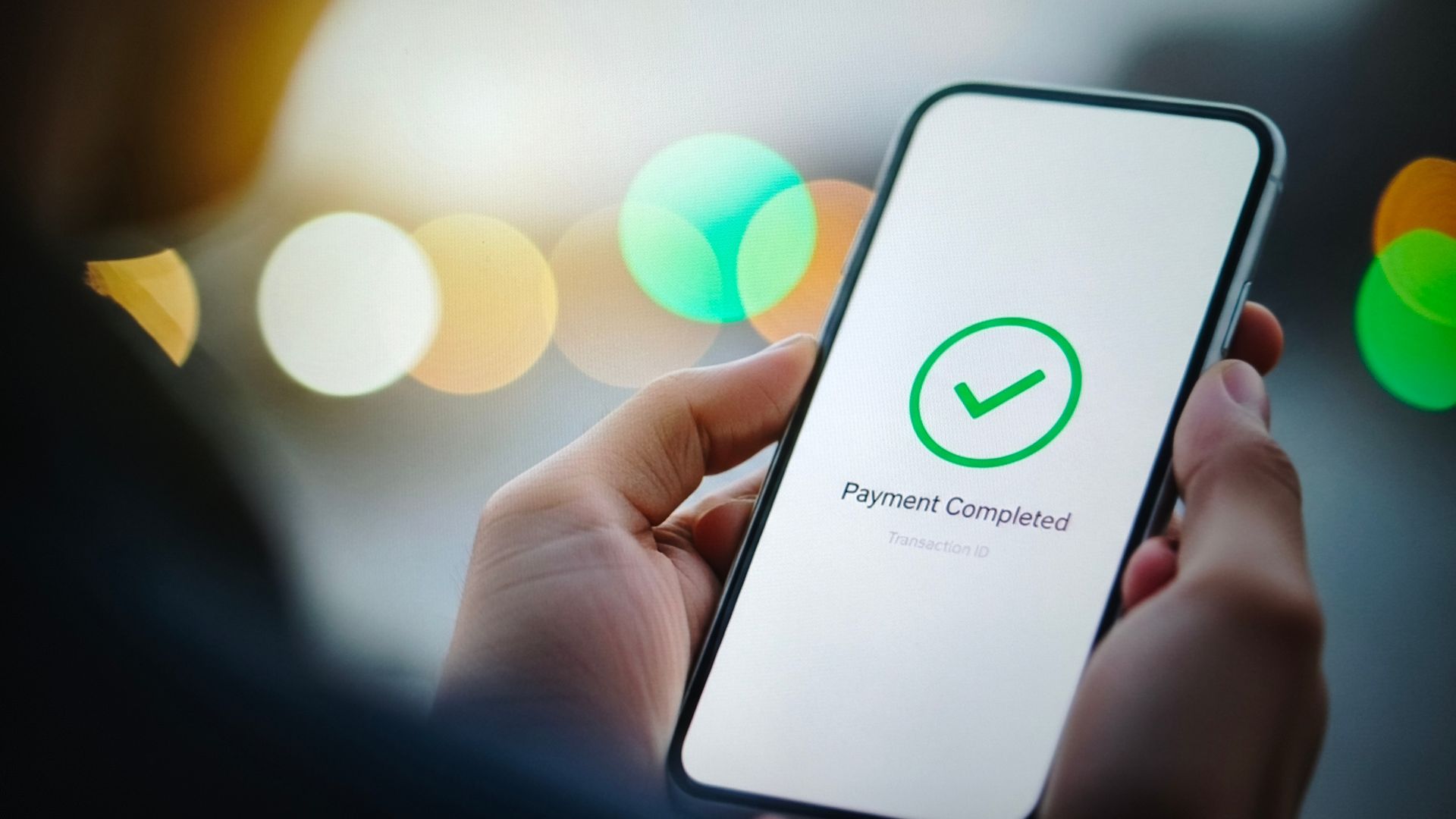 Hands holding a phone with a green check and “Payment Successful” message on a desk. | Dillsboro Automotive