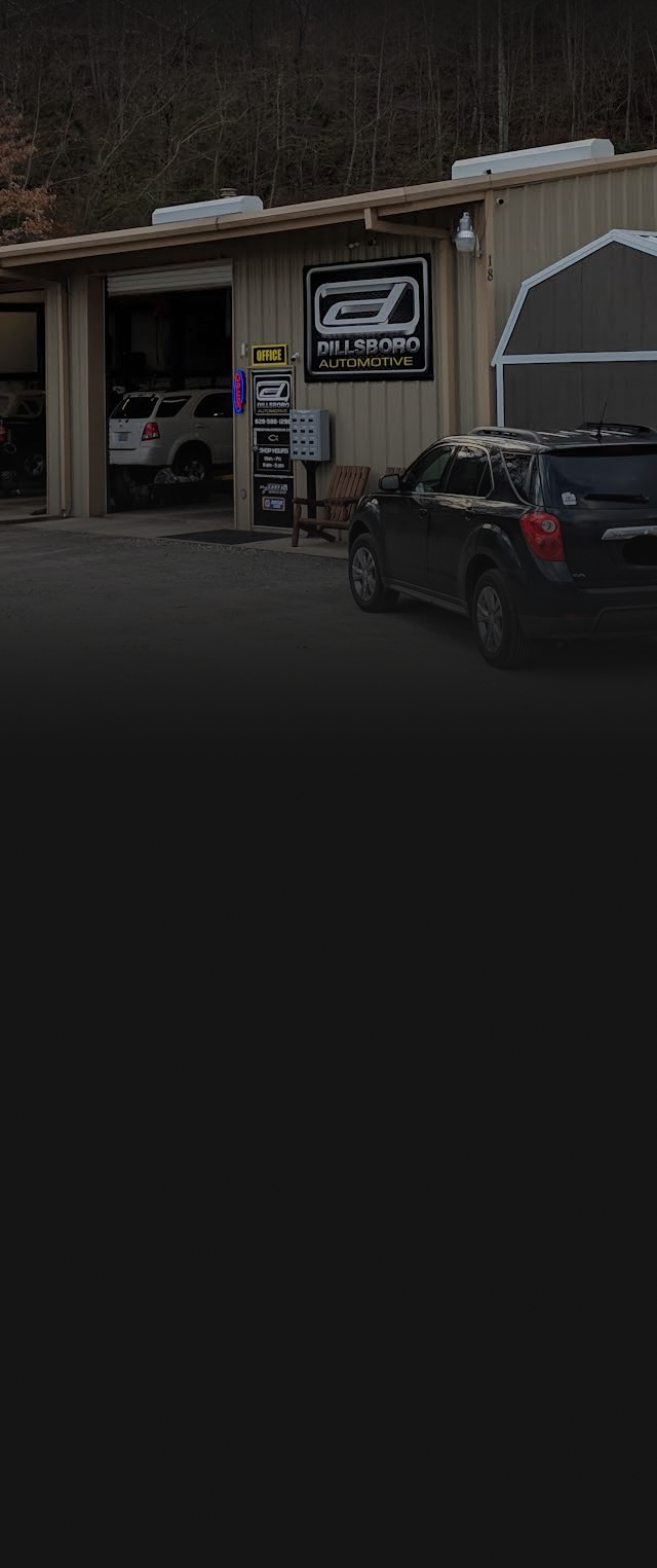 A small storefront with a sign, parked black car, and a covered awning in front. | Dillsboro Automotive