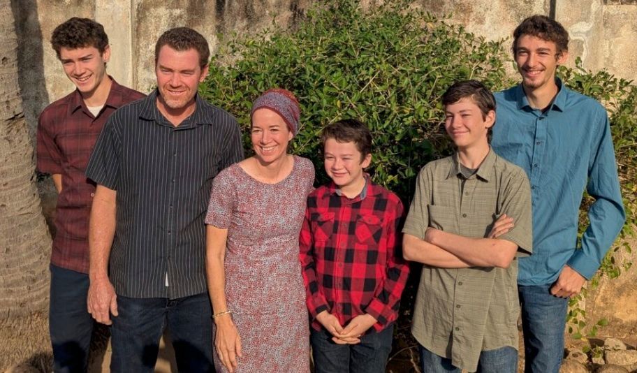 Five people standing outdoors in front of a tree, smiling at the camera.