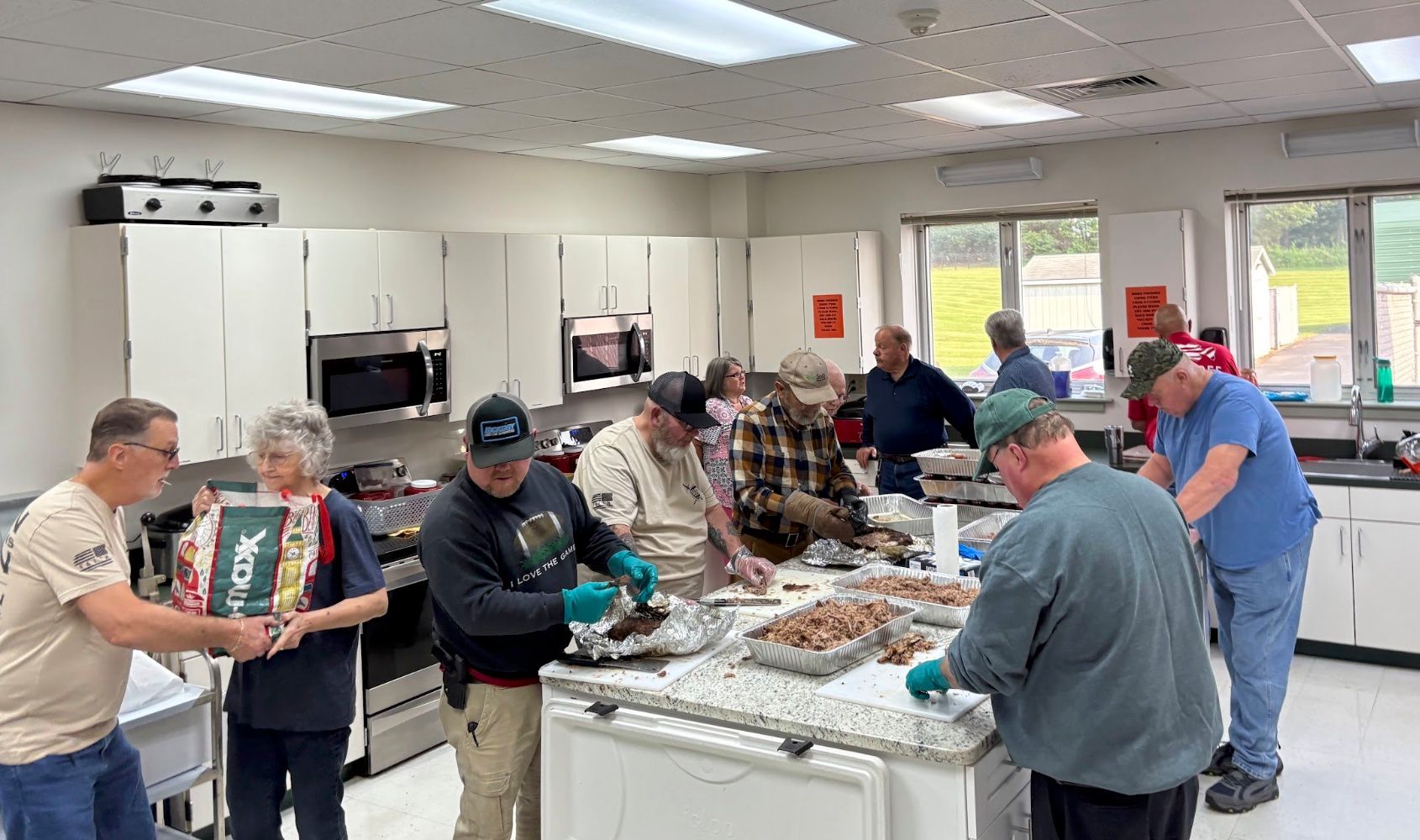 Volunteers serving food at a buffet in a bright community kitchen