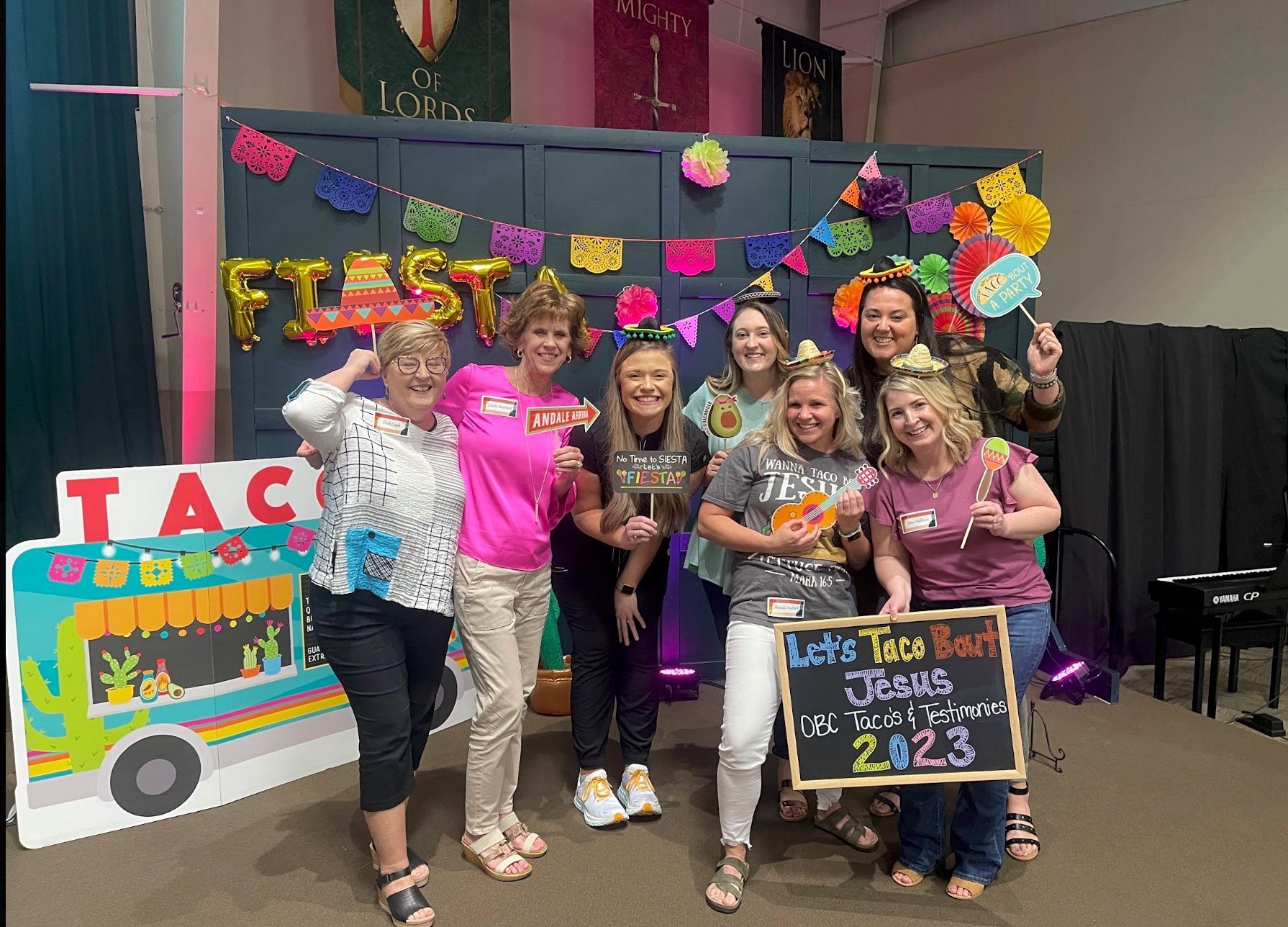 Group posing at a colorful graduation party with decorations and a decorated signboard.