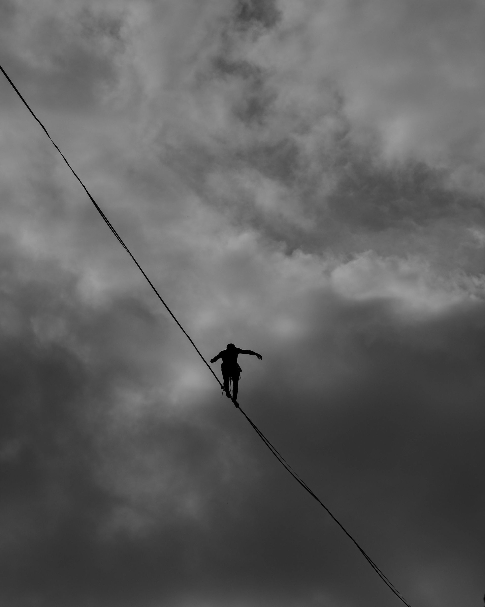 Person on tightrope under stormy sky, symbolizing leadership balance, focus, and navigating pressure