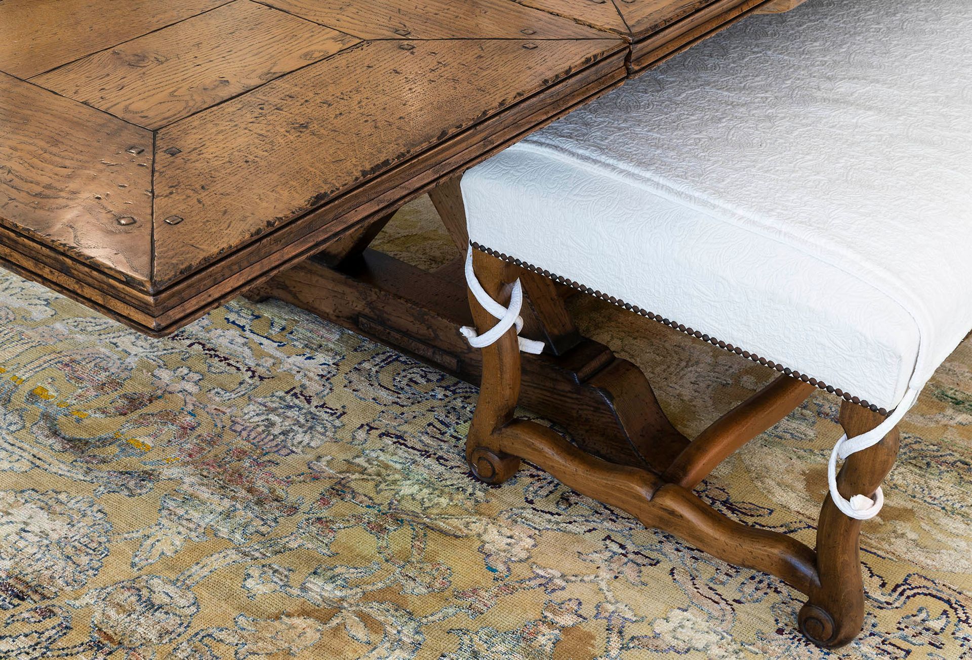 Wooden table overlapping a white-covered bench on a patterned rug — Shona O'Brien Interior Design in Bowral, NSW