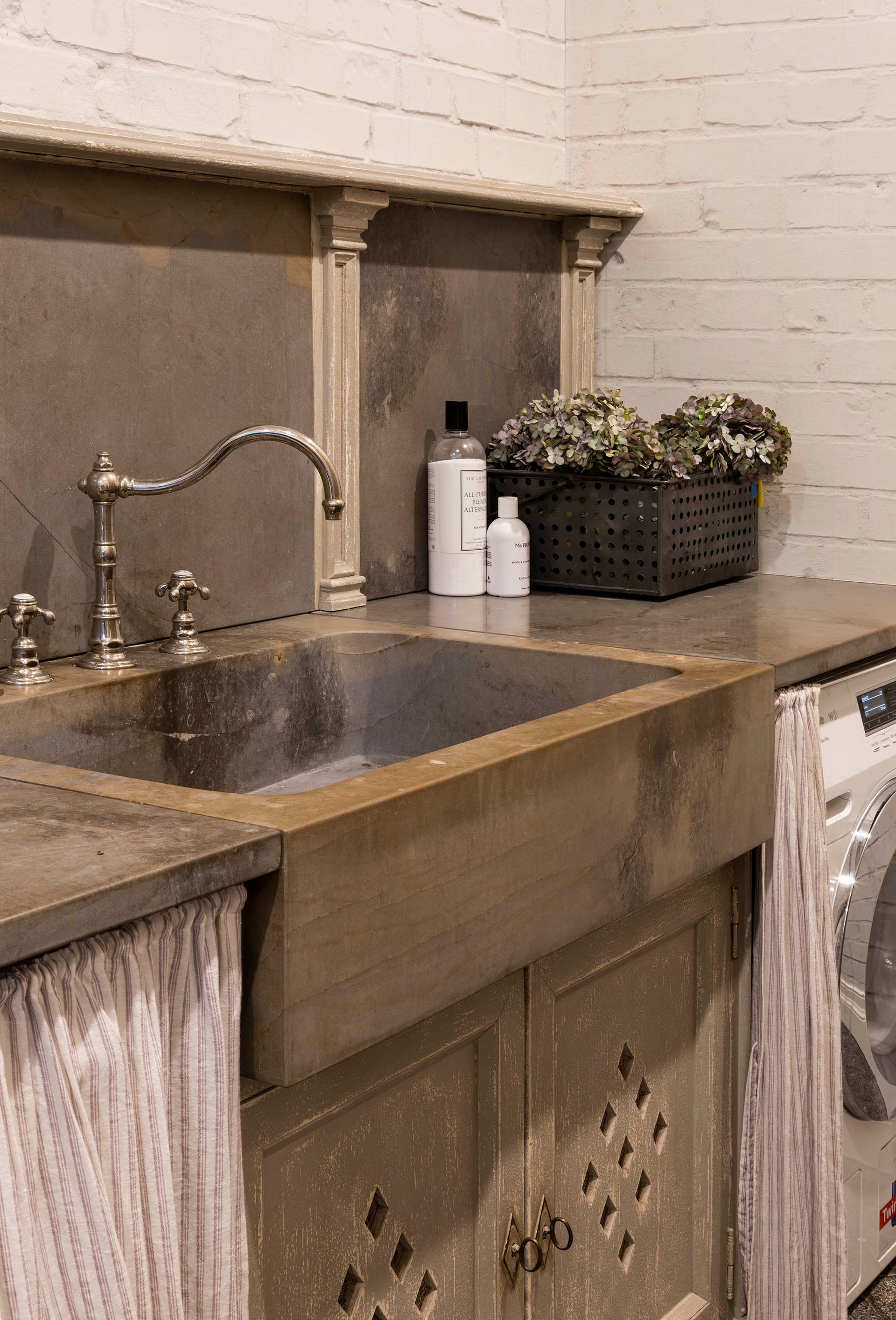 Laundry Room Sink With Metal Faucet, Countertop, Soap Bottles, And A Laundry Basket — Shona Design In Mittagong, NSW