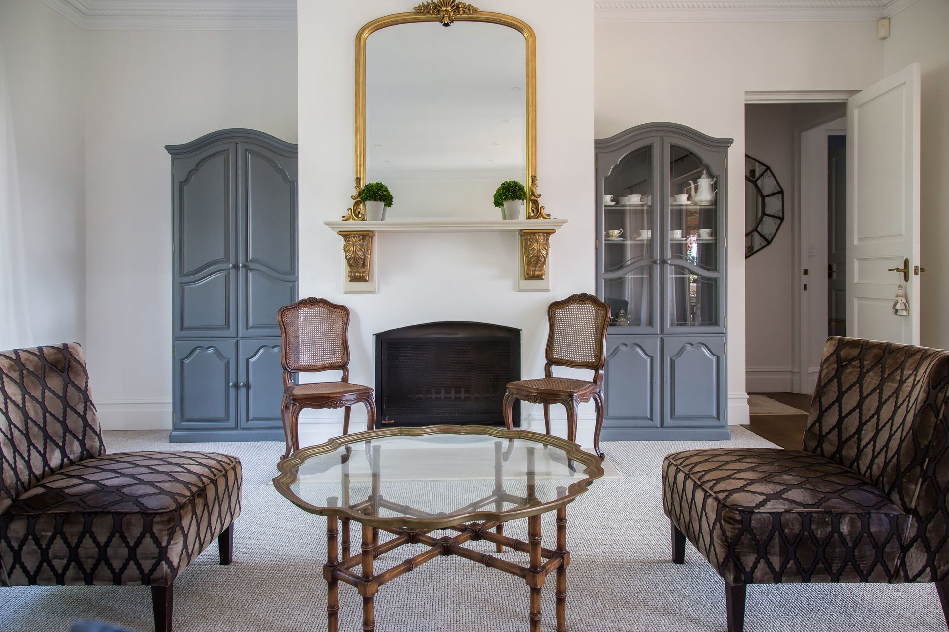 Elegant Living Room With Gray Chairs, Patterned Sofas, A Fireplace, And A Gold-framed Mirror — Shona Design In Mittagong, NSW