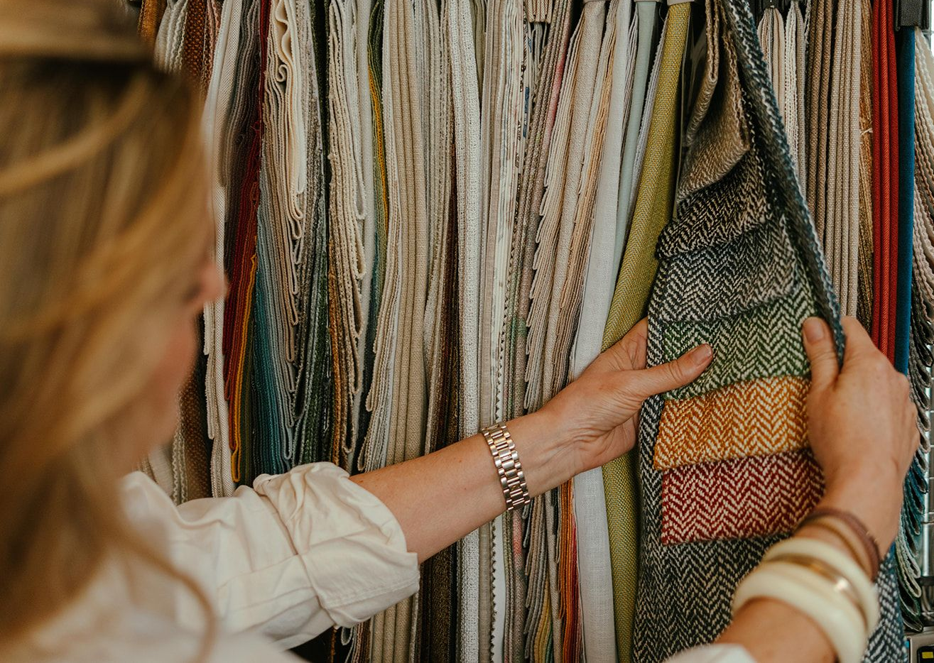 Person Browsing Colorful Fabric Samples on a Rack in a Textile Shop — Shona O'Brien Interior Design in Bowral, NSW