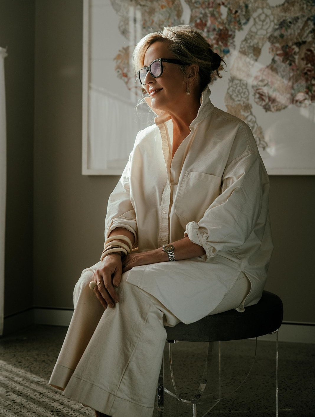 Woman in White Outfit Seated on a Stool in a Softly Lit Room — Shona O'Brien Interior Design in Bowral, NSW