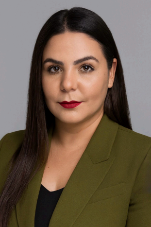 Ana Flavia Boughzala. A woman with dark hair and red lipstick, wearing a black shirt and forest green blazer.