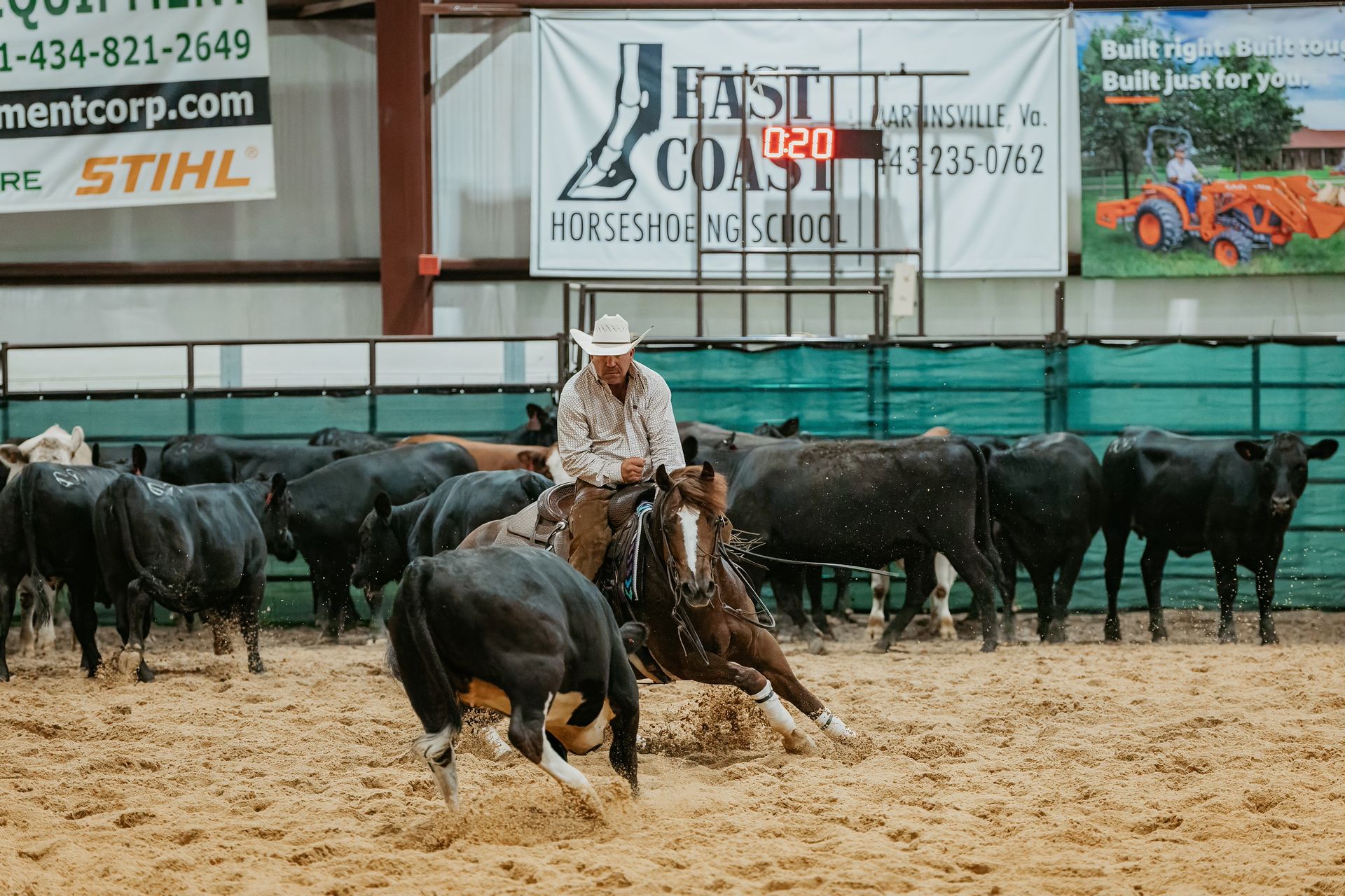 Cowboy on horseback cutting a cow from a herd in an arena.