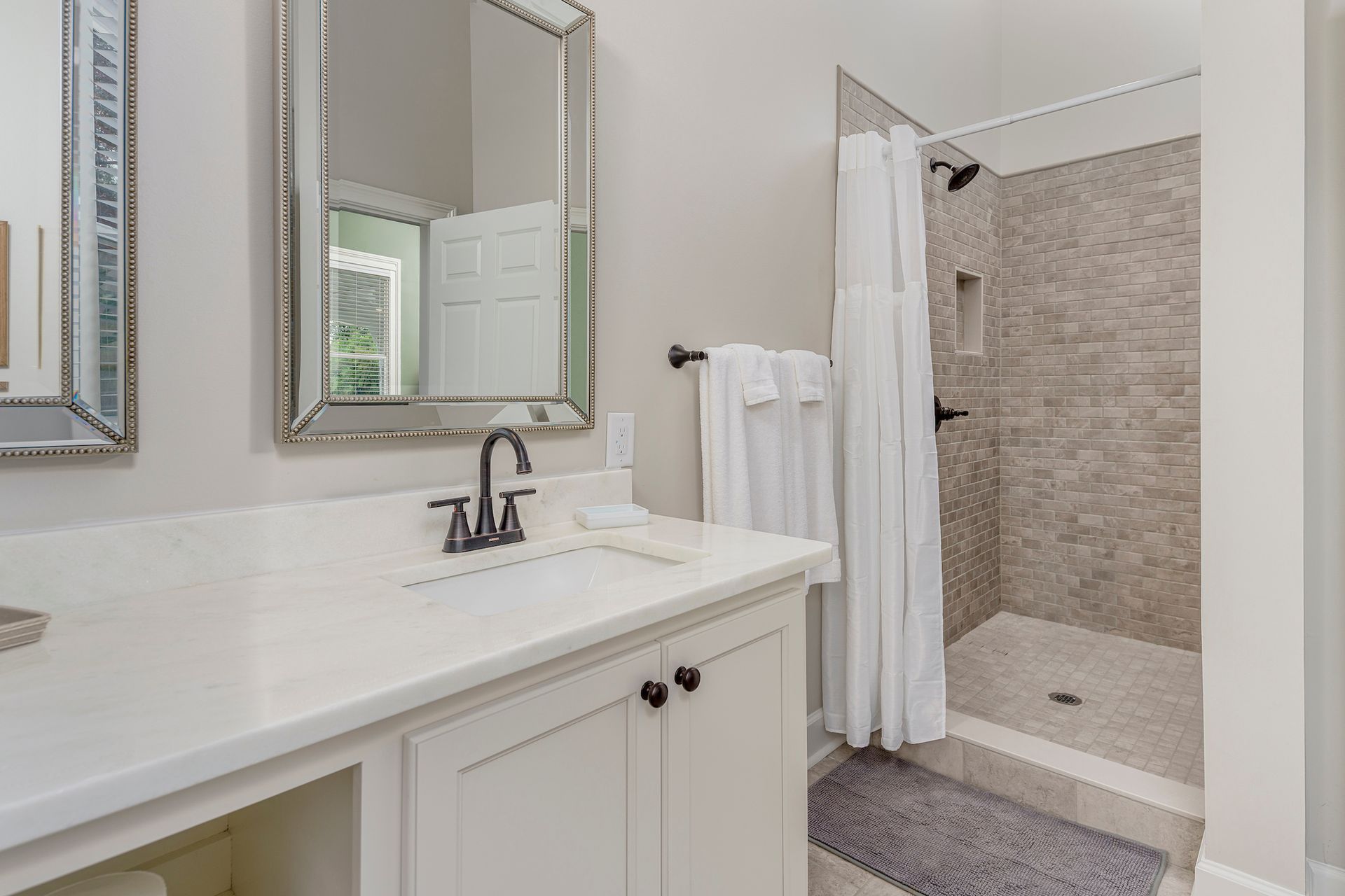 Bathroom with a white countertop, vanity, and walk-in shower. Gray and white color scheme.