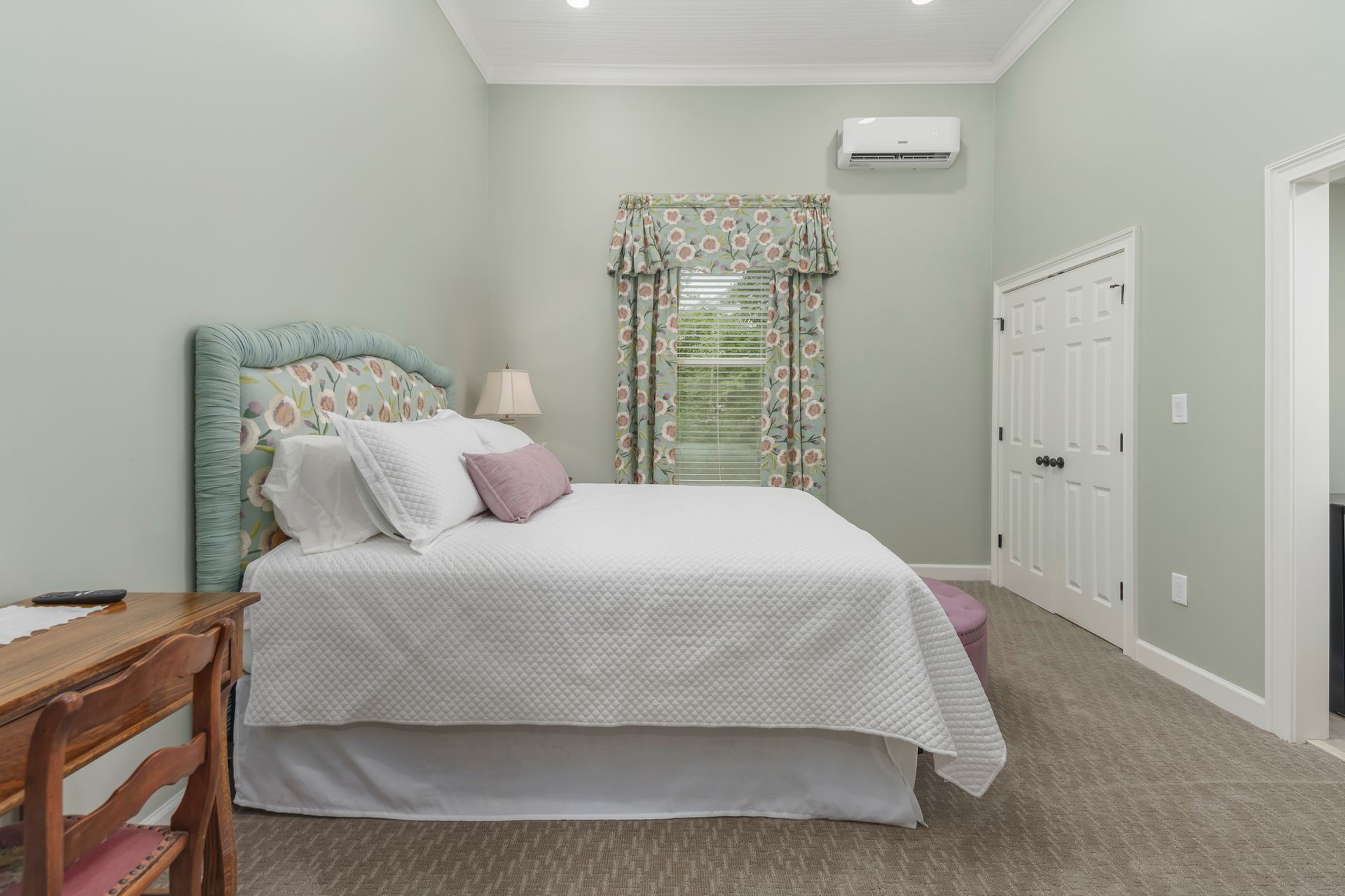Bedroom with a bed, desk, window, and closed closet door. Walls are light green.