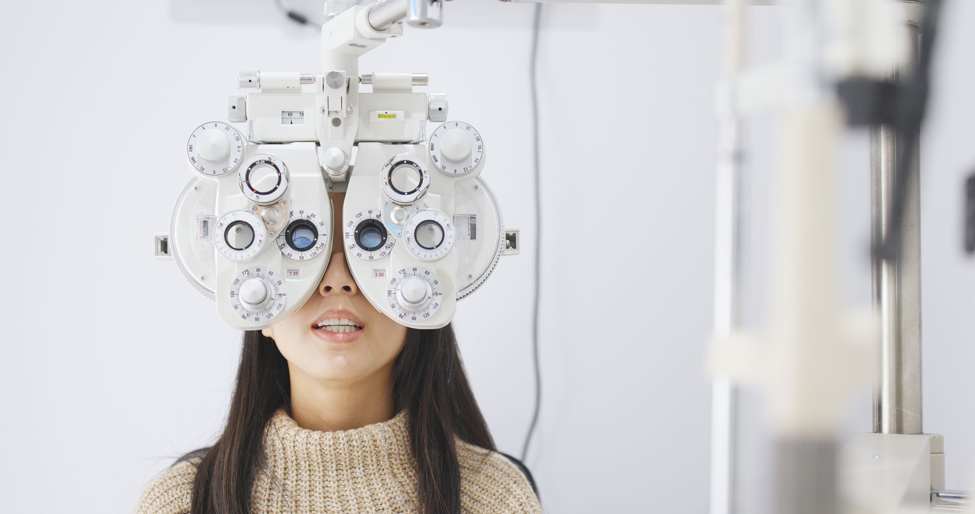 Person looking through a phoropter during an eye exam at an optometrist's office.