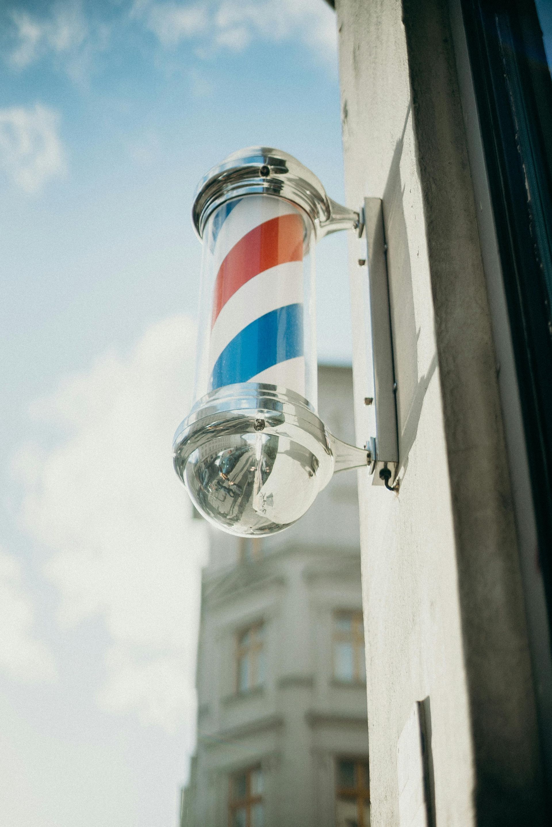 A barber pole is hanging on the side of a building.
