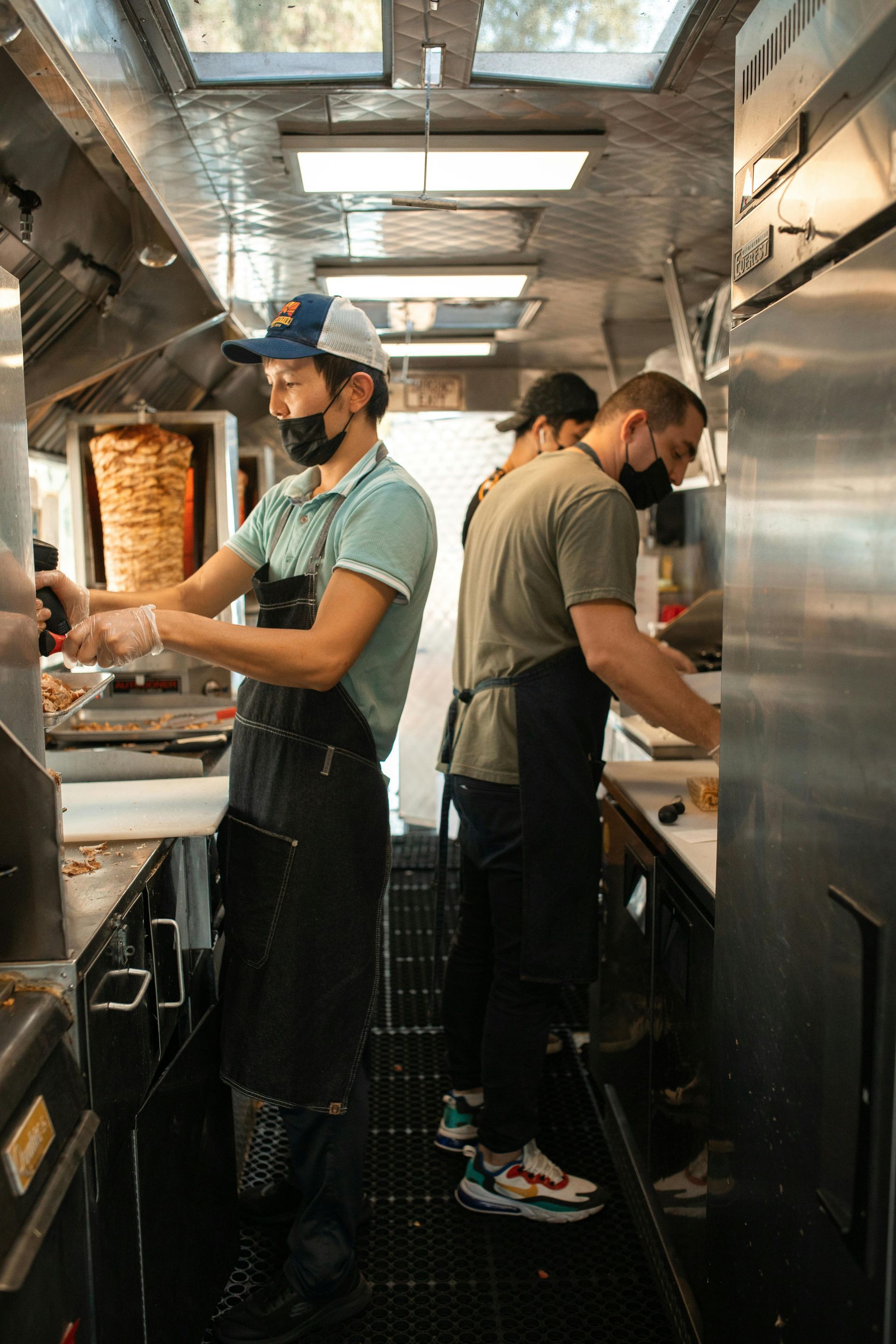 A group of men are standing in a kitchen preparing food.