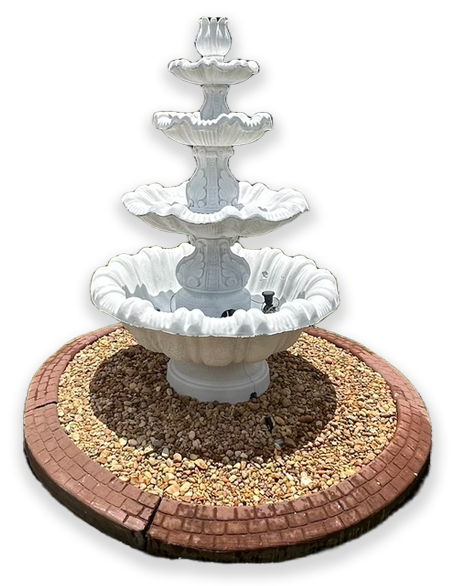 White tiered outdoor fountain on a bed of gravel surrounded by a brick border.