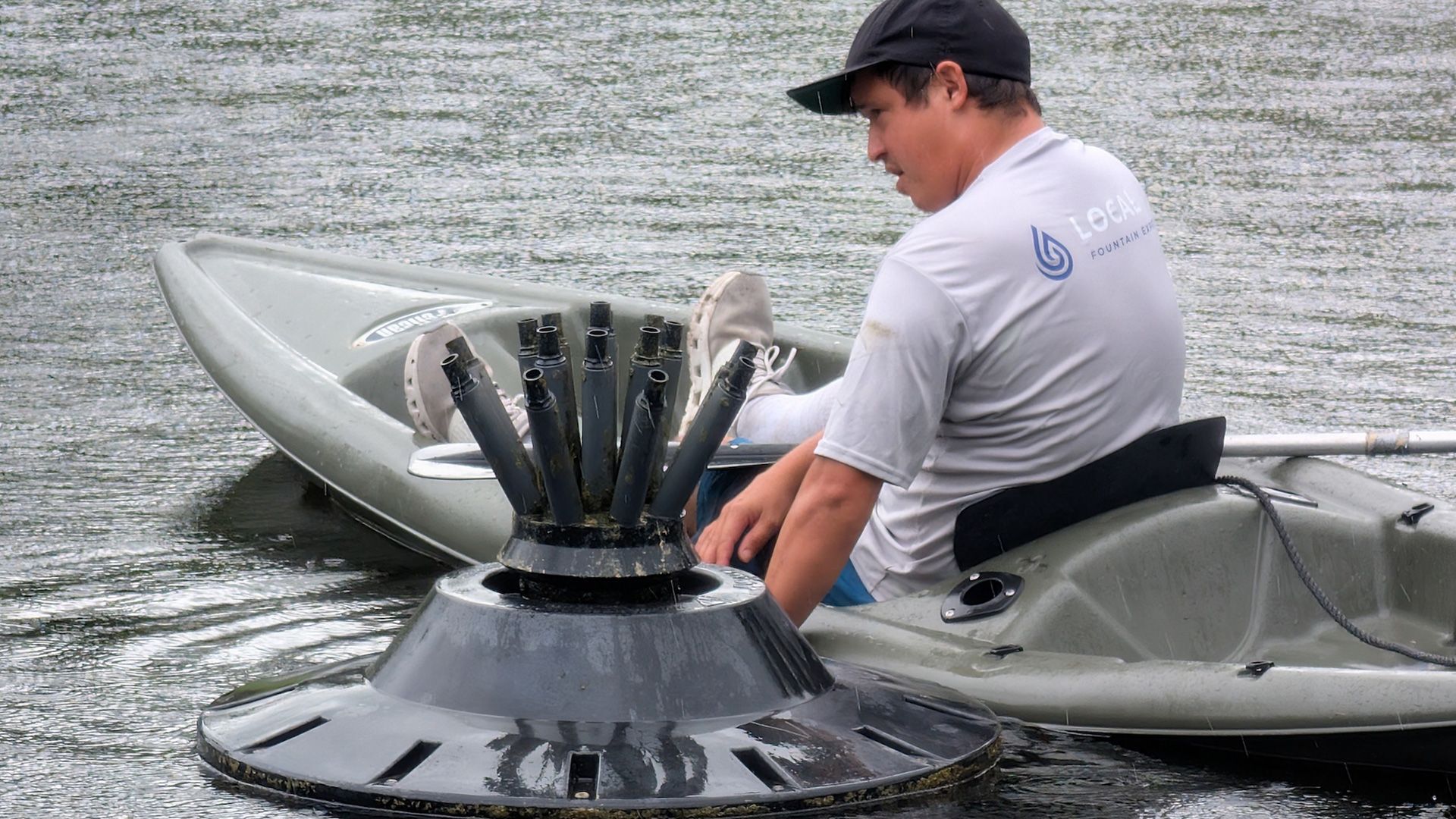 Man in kayak near floating water aerator.