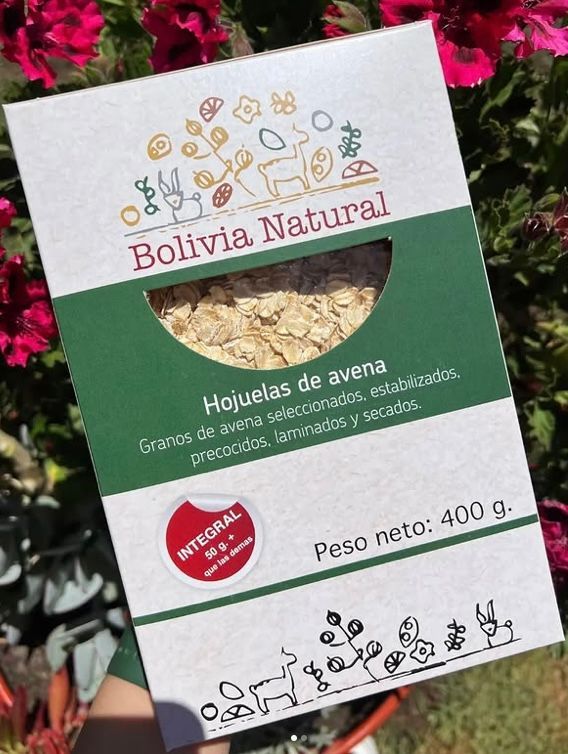 A bag of Bolivia Natural oat flakes held against a background of bright pink flowers.