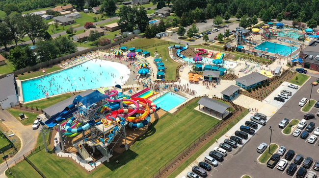 Aerial view of a colorful water park with pools, slides, and parking lot nearby
