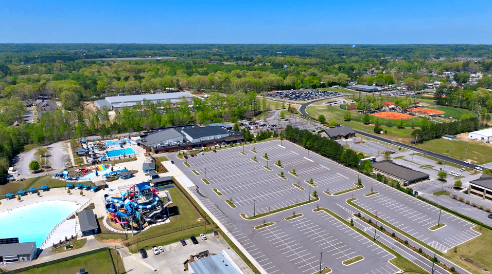 Aerial view of a large water park with pools, slides, and a big parking lot on a sunny day