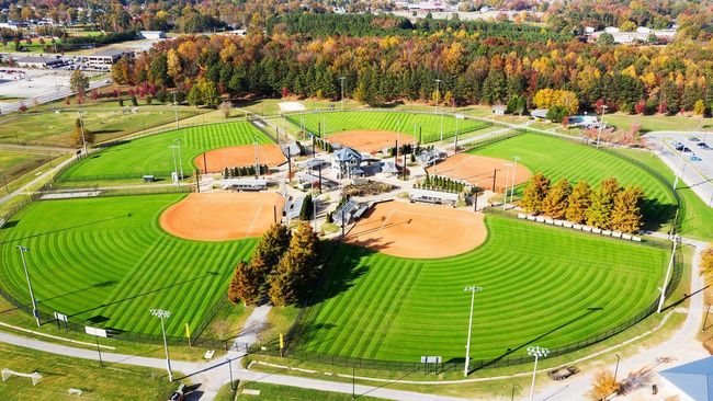 Aerial view of Heritage Park baseball fields with green grass, orange infields, and surrounding trees.