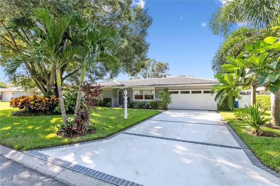 Sunny suburban house with palm trees, white driveway, and a two-car garage