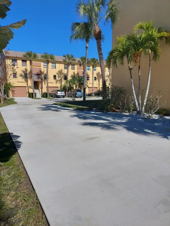 Palm-lined driveway leading to a tan apartment building on a sunny day