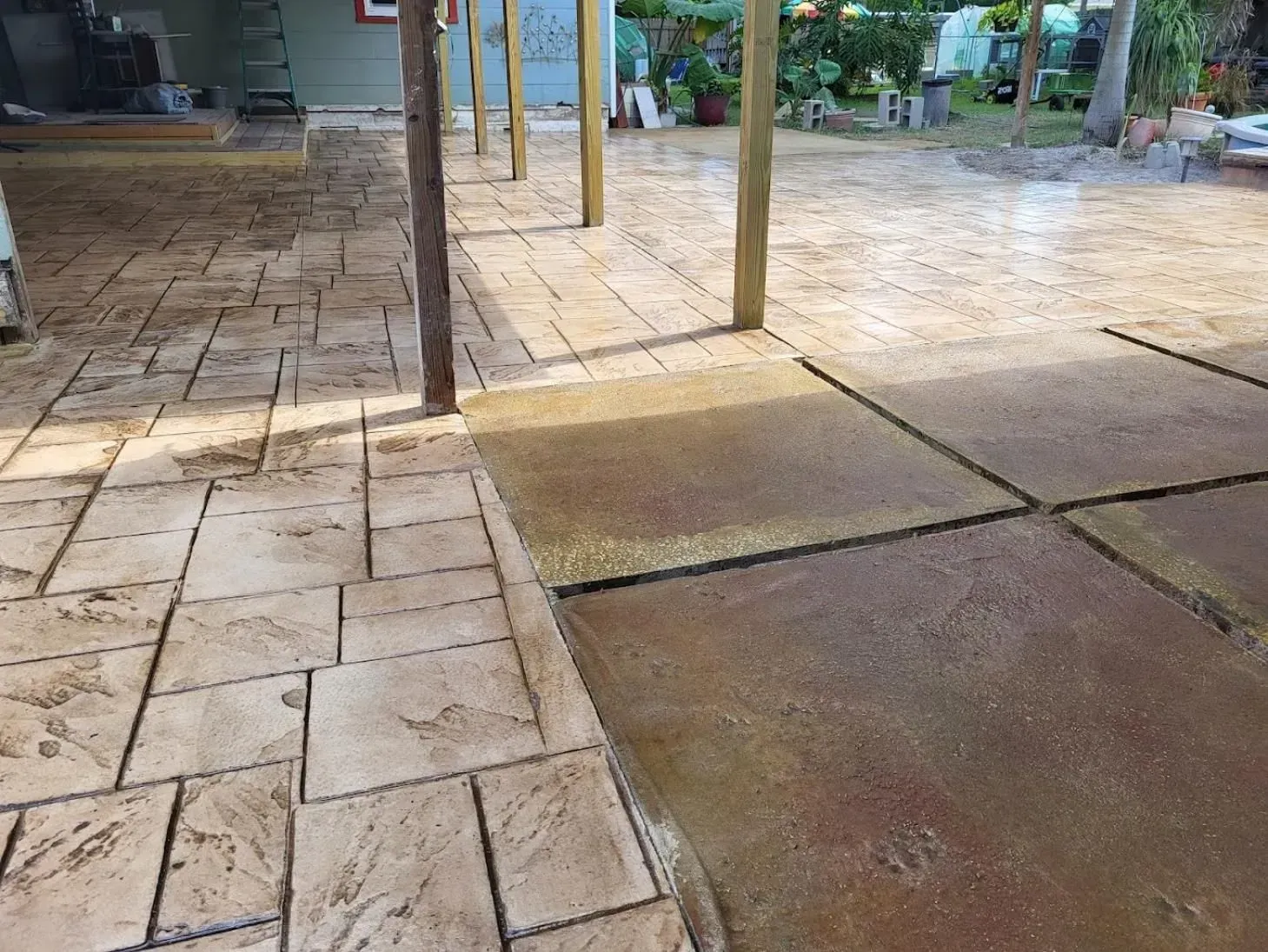Wet tiled patio with a covered walkway and garden area in the background