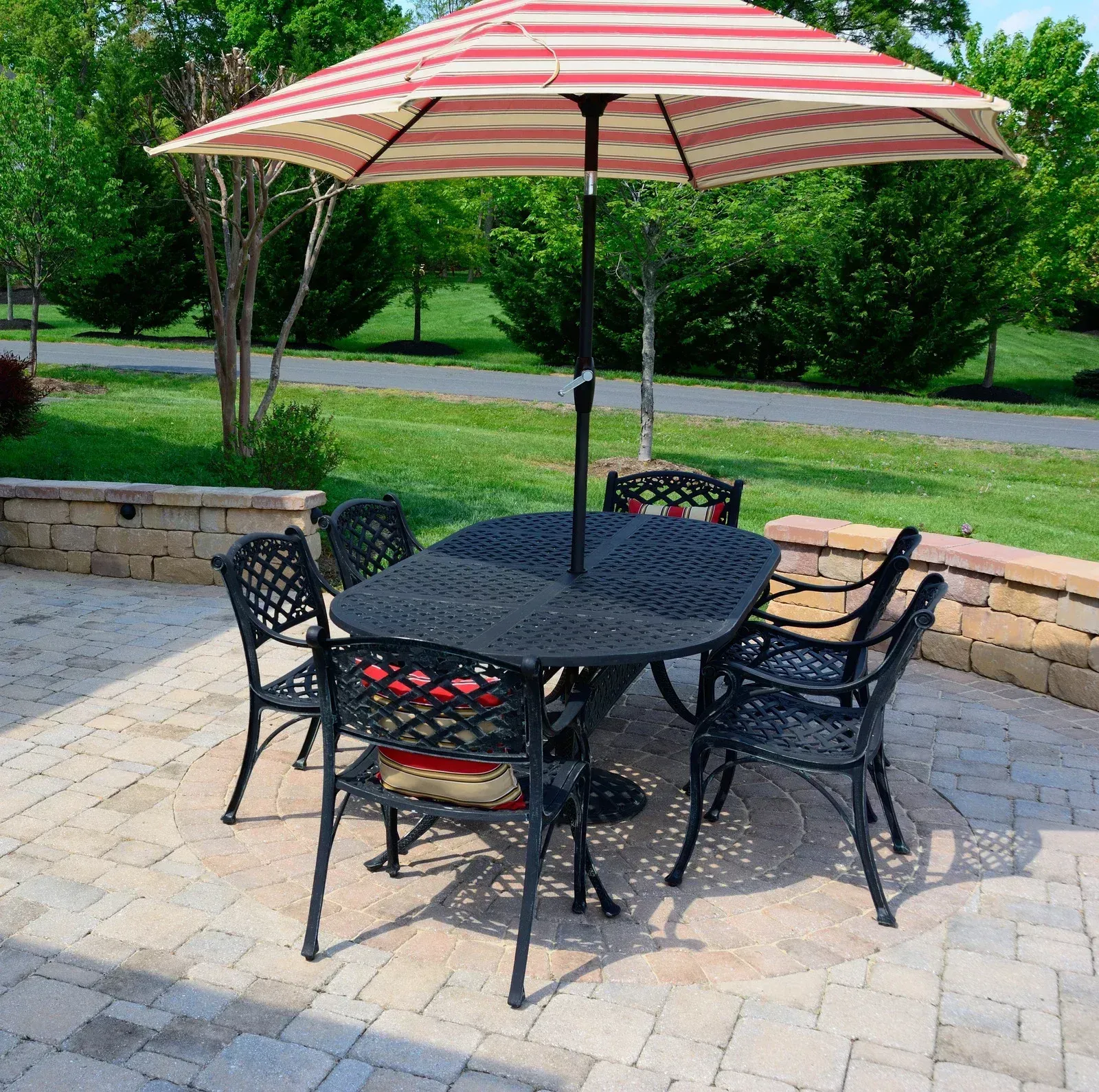 Patio table with four chairs under a red-and-white umbrella on a stone patio