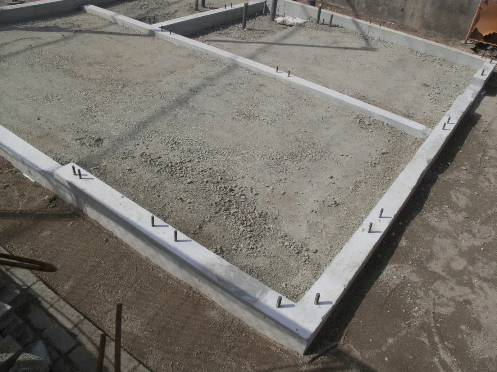Fresh concrete slab framed by white formwork on a construction site